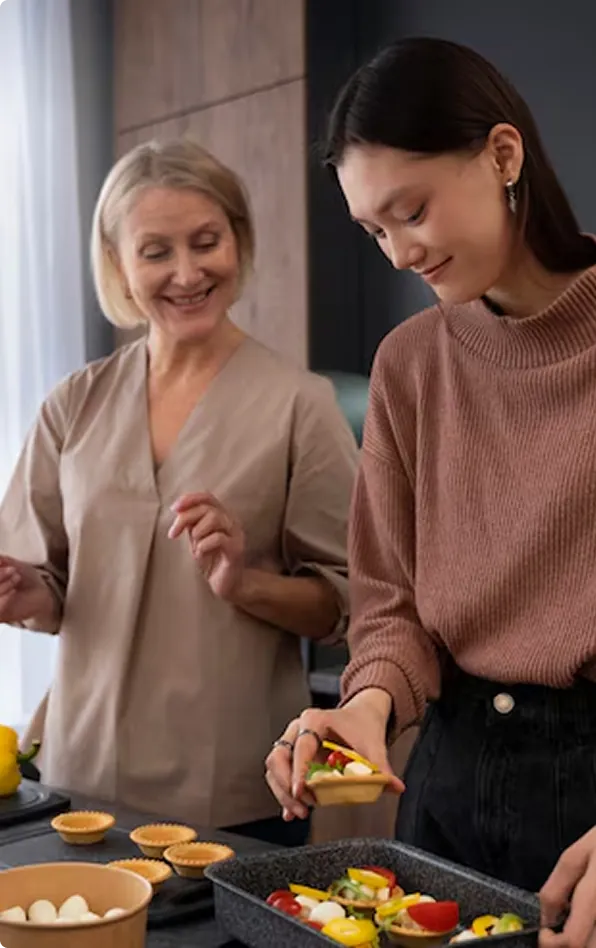 Elderly woman and younger caregiver cooking together