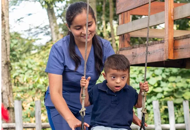 Healthcare worker helping a child on playground equipment